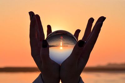 Close-up of man holding crystall ball at sunset