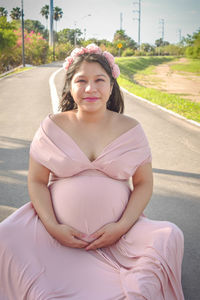 Portrait of a smiling young woman sitting on road