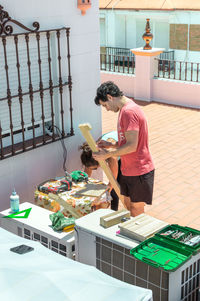 Couple building a piece of furniture on a rooftop on a sunny day.