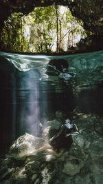 Woman with face paint by rock formation underwater