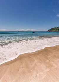 Scenic view of beach against blue sky