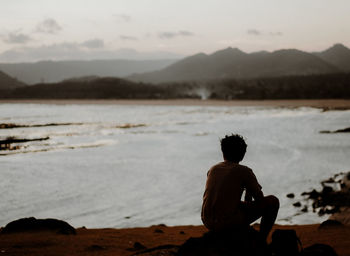 Rear view of man sitting on beach