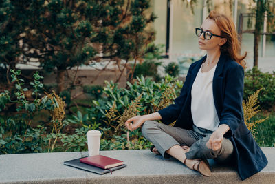 Young woman sitting by plants