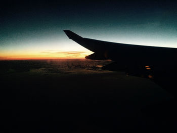 Airplane flying over landscape at sunset