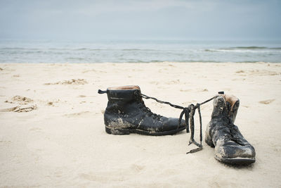 High angle view of shoes on sand at beach against sky