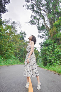 Full length of woman standing on road against trees