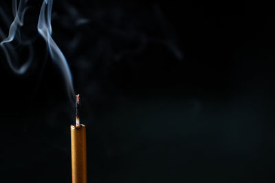 Close-up of emitting smoke against black background