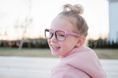 Portrait of a young girl with a bun and pink sparkly glasses on