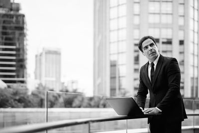 Full length of man standing in front of office buildings