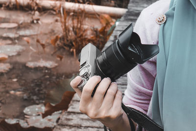 Midsection of man holding camera outdoors