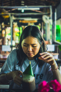 Portrait of a young woman drinking glass at restaurant
