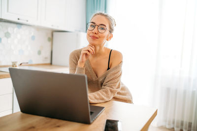 Portrait of young woman using laptop on table