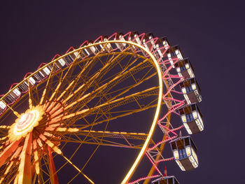 Low angle view of illuminated ferris wheel against sky at night