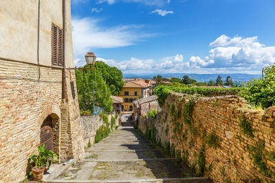 Footpath amidst buildings against sky