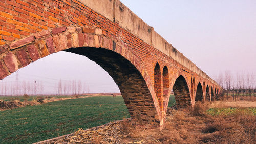 Arch bridge on field against clear sky