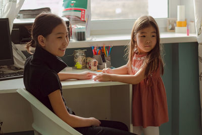 Two sisters teen and girl child drawing together at home, happy family life and candid lifestyle