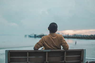 Rear view of man looking at sea against sky