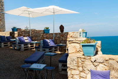 Chairs and tables on beach against sky