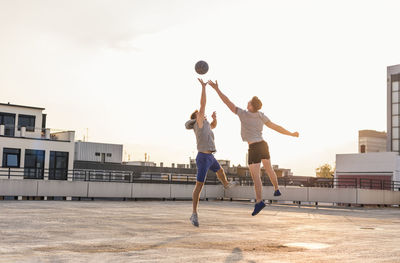 Friends playing basketball at sunset on a rooftop