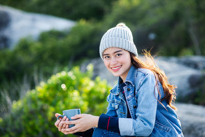 Portrait of smiling young woman using mobile phone