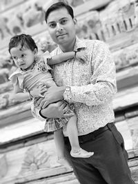 Portrait of father carrying daughter while standing outdoors