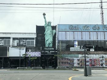 Statue on city against sky