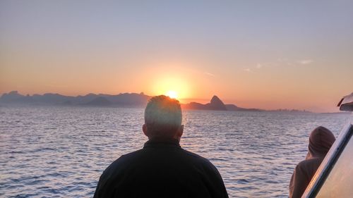 Men standing against sea during sunset