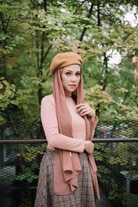 Portrait of woman standing against railing and trees