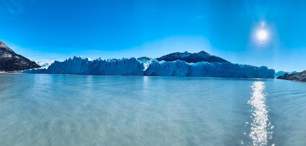 Scenic view of sea and mountains against blue sky