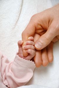 Close-up of baby holding hand of mother 