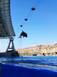 Man paragliding over sea against clear blue sky