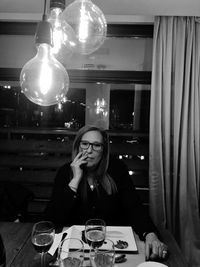 Portrait of young woman sitting on table in restaurant