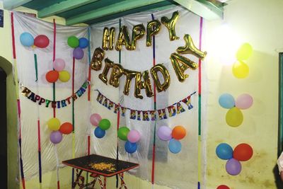 Close-up of multi colored balloons hanging against wall in building