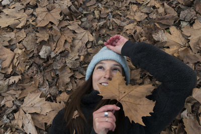 High angle view of smiling woman lying on autumn leaves