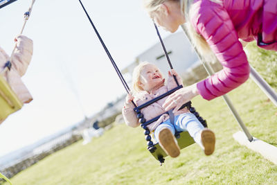 Mother swinging daughter