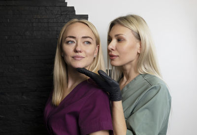 Portrait of young woman standing against wall