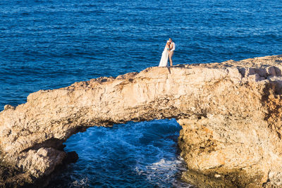 Man standing on rock by sea