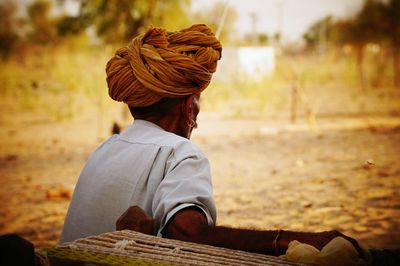 Rear view of indian man sitting on field