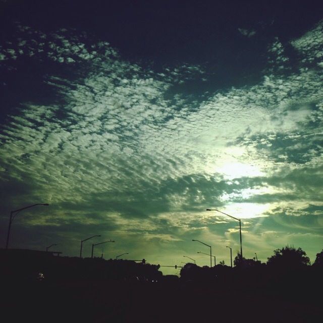 silhouette, sky, sunset, cloud - sky, tranquility, beauty in nature, tranquil scene, tree, nature, street light, scenics, dark, low angle view, sun, sunlight, cloudy, outdoors, cloud, no people, electricity pylon