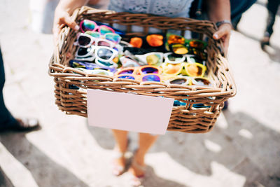 Low section of woman holding sunglasses in basket