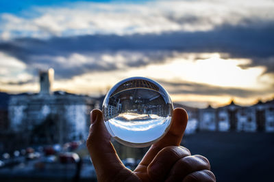 Close-up of hand holding glass against sky