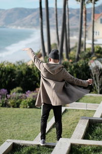 Rear view of woman standing against trees