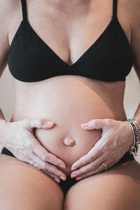 Midsection of pregnant woman touching stomach at home