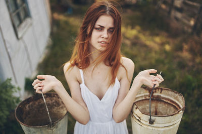 Portrait of woman holding buckets while standing outdoors