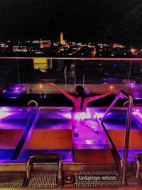 Midsection of woman sitting in illuminated city at night