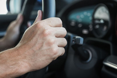 Cropped hand of man driving car