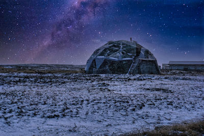 Built structure on snow covered land against sky at night