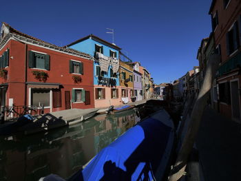 Canal amidst buildings against blue sky