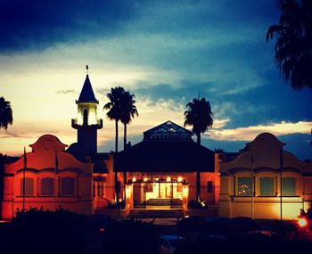 Silhouette buildings and trees against sky at sunset