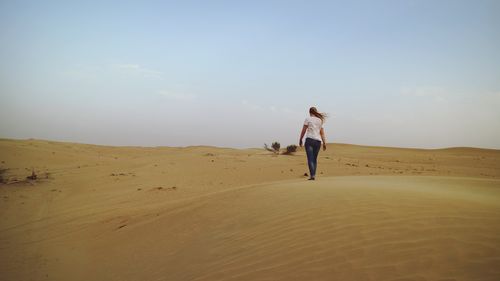 Rear view of man on beach against clear sky